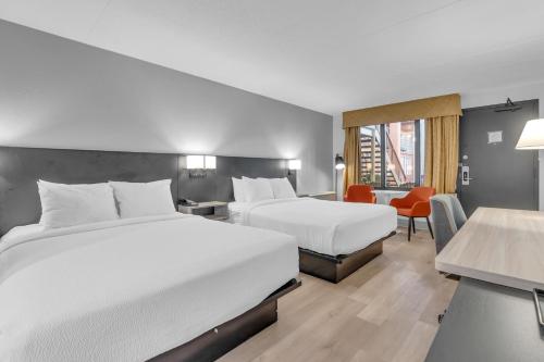 a hotel room with two beds and a desk at Seven Oaks Hotel Regina in Regina