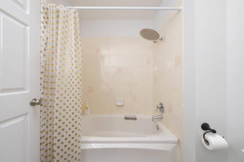 a bathroom with a tub and a shower curtain at Surrey Family Home w/ Patio & Garden – 3BR 2BA in Guildford