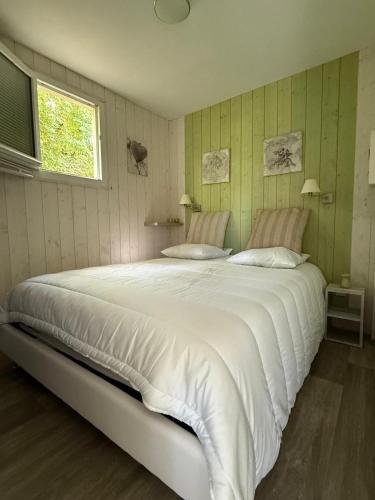 a bedroom with a large white bed with a window at Les Cabanes du Lac à Surgères in Vandré