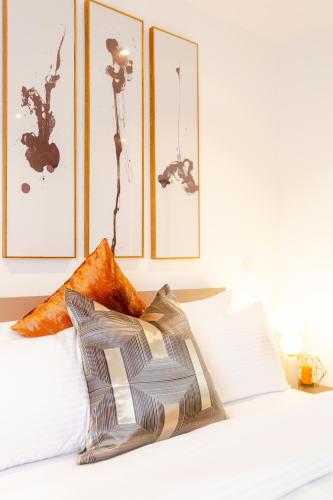 a bed with two pillows and three pictures on the wall at Accra Luxury Apartments @ The Lennox in Accra