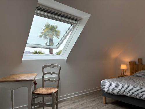 a bedroom with a window and a table and chair at Maisonnette bretonne typique Beg Meil Fouesnant Ty Breizh plage in Fouesnant