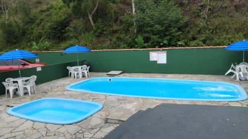 una grande piscina blu con sedie e ombrelloni di toninhas 300 mts mar a Ubatuba