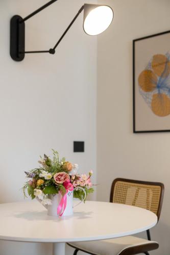 a white table with a vase of flowers on it at Castello Blu Suite in Sesto Fiorentino