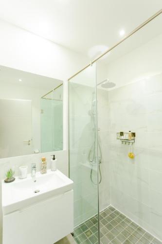 a white bathroom with a shower and a sink at Accra Luxury Apartments @ The Lennox in Accra