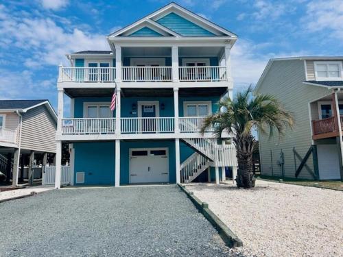 a blue house with a palm tree in front of it at 218 Brunswick home in Holden Beach