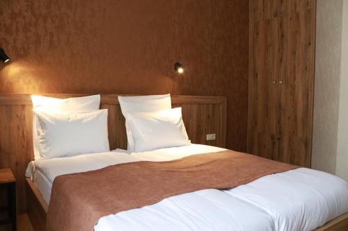 a bedroom with a large bed with white sheets and pillows at Hotel 717 Kazbegi in Stepantsminda