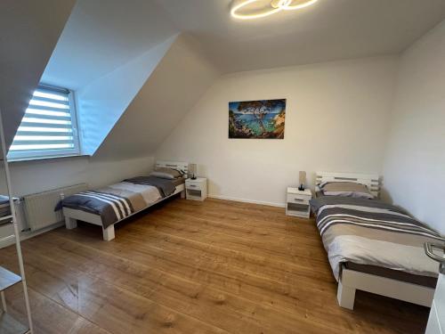a attic room with two beds and a window at DERKO Apart 2 in Duisburg