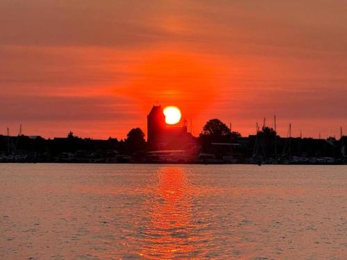 a sunset over the water with a building in the background at Holiday Home in Yn e Lijte with Water Sports in Grou
