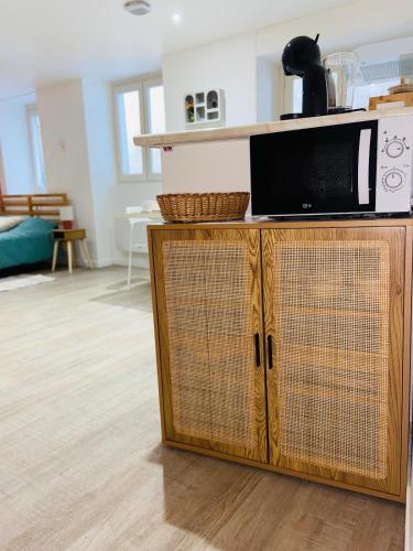 Un four micro-ondes est installé au-dessus d'une armoire en bois. dans l'établissement Terracotta, Appartement, Centre historique, à Auch