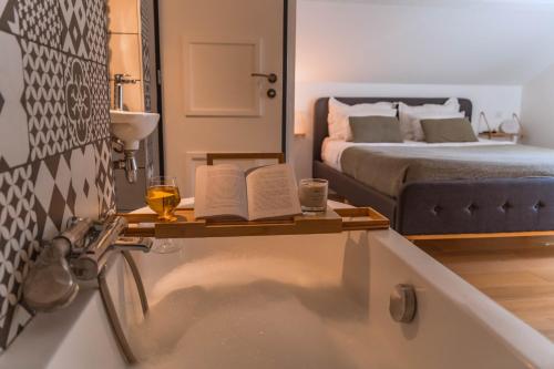 a bathroom with a bath tub with a bed and a mirror at Villa de Charme avec Piscine Calme & Élégance in Aubenas