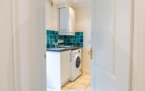 a kitchen with a washing machine and a washer and dryer at Ottery House in Westhampnett