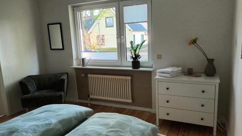 a bedroom with a bed and a window and a chair at Ferienwohnung Haus-Holly 2 in Uetersen