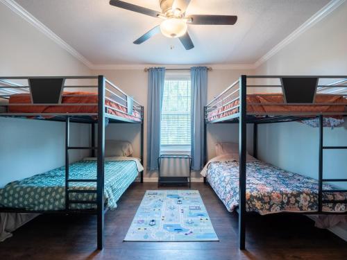 two bunk beds in a room with a ceiling fan at Luxury At Meadowbrook, Pool Home, Fire Pit, Fort in Valdosta