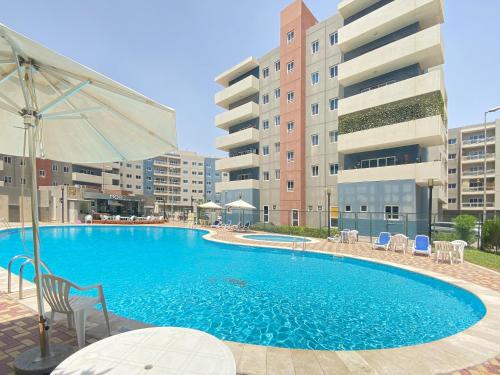 a large swimming pool with chairs and an umbrella at Modern Oasis - Elegant Cave - Family Heaven - Designer's Paradise - 10 min away from Abu Dhabi Airport, Yas Island, Formula 1, Ferrari World, SeaWorld, Warner Bros World in Abu Dhabi