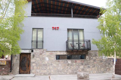 a white building with windows and a stone wall at Hotel 717 Kazbegi in Stepantsminda