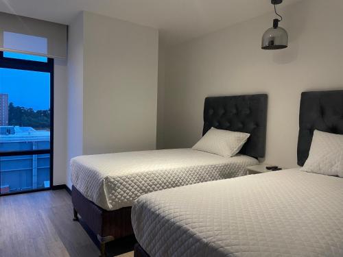 a hotel room with two beds and a window at Lujoso Apto 2 habitaciones cerca Oakland Place Zona 10 GT in La Aurora