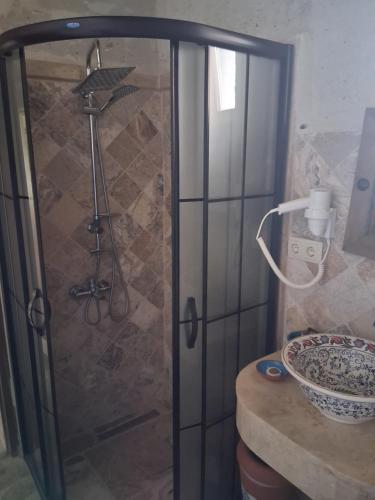 a shower with a glass door and a bowl on a counter at Kemerli House in Avanos