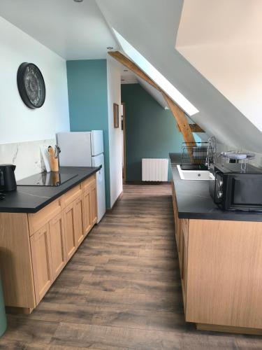 une cuisine avec des comptoirs noirs et un escalier dans l'établissement Gîtes les Bon' aparte, à La Chapelle-sur-Loire