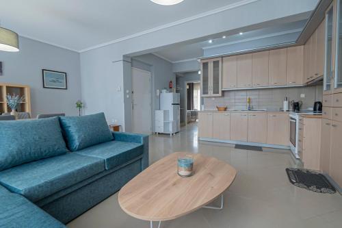 a living room with a blue couch and a wooden table at M&P Apartment by RentalsPro - Nea Moudania Halkidiki in Nea Moudania
