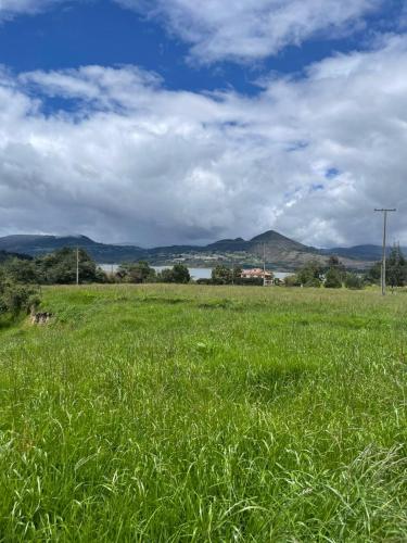 a field of green grass with mountains in the background at El Alpino Cabaña Glamping & Camping in Guatavita