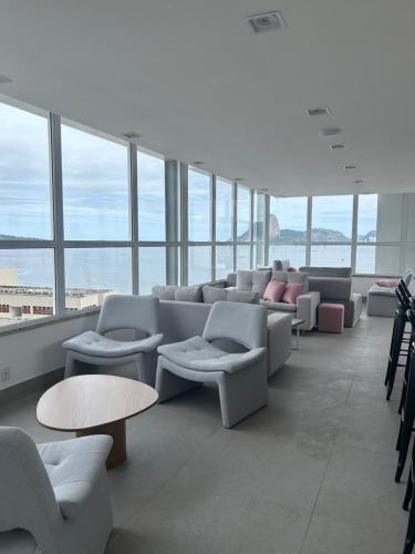 a waiting room with couches and tables and windows at Studio moderno e novo perto do MAC - UNI Home 113 - Boa Viagem in Niterói