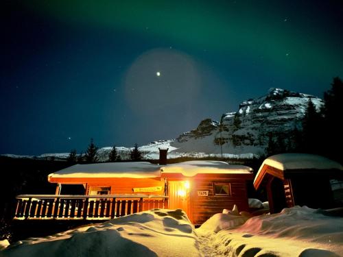 a cabin in the snow at night with a mountain at Maxi Cabin with Sauna and Jacuzzi in Kovan