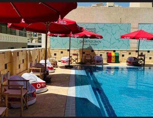 - une piscine avec des parasols et des chaises dans l'établissement Downtown new Alamain apartments near Rixos El Alamain, à El Alamein