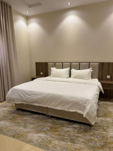 ein Schlafzimmer mit einem großen Bett mit weißen Laken und Kissen in der Unterkunft شقق الأول للشقق المخدومة in Quai