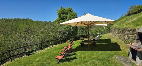 a table and benches with an umbrella on the grass at Borgo Tramonte in Pratovecchio