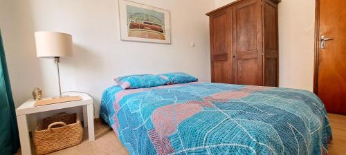 a bedroom with a bed with a blue comforter at Mazet en provence pour 4, piscine chauffée privée, jardin clos privé, barbecue, chiens admis in Sainte-Jalle