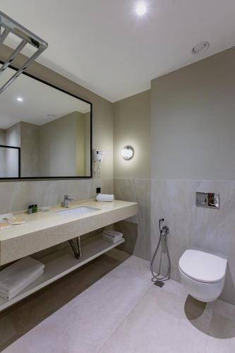 a bathroom with a sink and a toilet and a mirror at Monte Napoleone Hotel in Baku