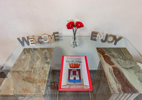 a table with a vase of red roses and a sign at La Fortezza Exclusive - Spazio e Relax in Centro in Livorno