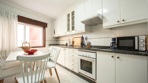 a kitchen with white cabinets and a table and chairs at Casa Marinera en A Guarda in A Guarda