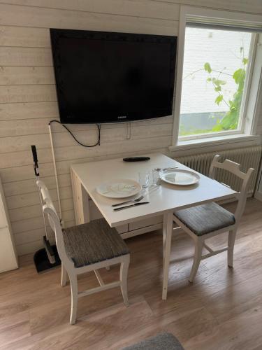 a white table with two chairs and a television at Seaside Escape Cozy Cottage 2 Min from the Beach in Halmstad