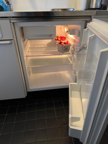 an open refrigerator with a box of strawberries in it at Seaside Escape Cozy Cottage 2 Min from the Beach in Halmstad