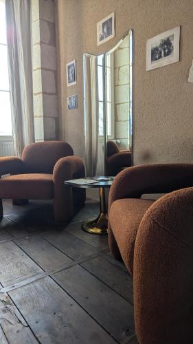 une pièce avec deux chaises, une table et un miroir dans l'établissement Maison Nathis, à Saint-Sulpice-de-Roumagnac