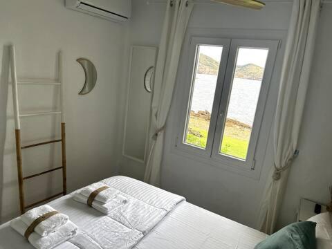 a white bedroom with a bed with a window at Miravent Terraza y Jardin Frente al mar Menorca in Fornells