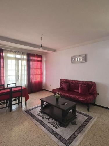 a living room with a red couch and a table at bord de mer F3 1 in Tigzirt