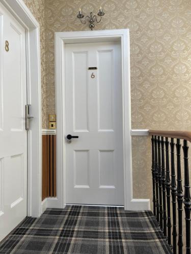 a white door in a hallway with stairs at Kingston Guesthouse in Edinburgh