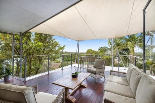 a living room with a table and chairs on a balcony at Luxe & Spacious Gem with Pool, Ocean Views, Snooker Table in Alexandra Headland
