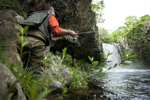 a man standing in a river holding a fishing rod at Villa de Charme avec Piscine Calme & Élégance in Aubenas