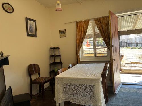 a dining room with a table and chairs and a window at The Smelters Home Burra in Burra