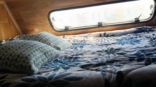 a bed with pillows in a room with a window at Autocaravana para pasar la noche in Puertito de Güímar