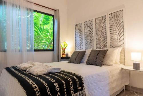 a bedroom with a bed with white sheets and a window at La Prometida in Puerto Viejo