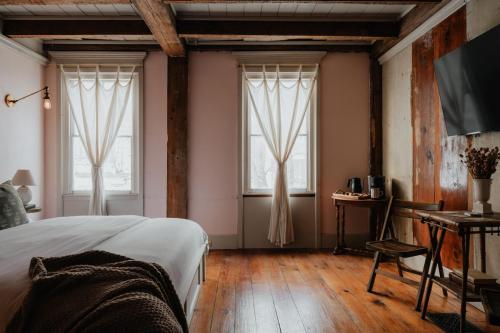 a bedroom with two windows and a bed and wooden floors at Book Village Inn - Fitzgerald Room King Bed in Hobart