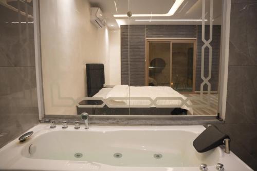 ein Badezimmer mit Badewanne und einem Bett in einem Spiegel in der Unterkunft Lumen villa in Umm Uthainah