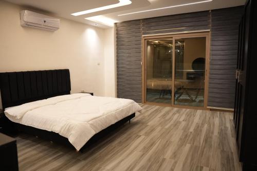 ein Schlafzimmer mit einem Bett und einer Glasschiebetür in der Unterkunft Lumen villa in Umm Uthainah