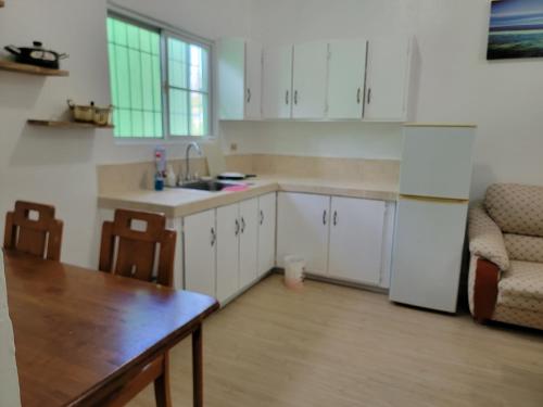 a kitchen with white cabinets and a table and a refrigerator at Green Flash Dive Inn in Garapan