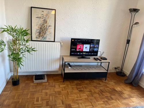 Cette chambre comprend une table et une télévision. dans l'établissement Joli appartement à Montreuil, proche des nouvelles stations de métro, à Montreuil