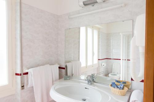 a white bathroom with a sink and a mirror at Club Hotel Olivi - Tennis Center in Malcesine